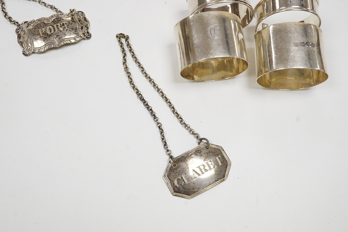 Four silver napkin rings including a pair, Sheffield, 1919, together with two George III silver wine labels, Claret, maker probably Abstinando King and Port, maker James Phipps I.